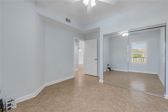 unfurnished bedroom with light tile patterned flooring, a closet, and ceiling fan