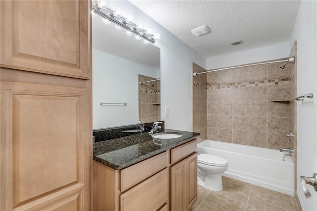 full bathroom featuring toilet, tile patterned floors, tiled shower / bath, vanity, and a textured ceiling