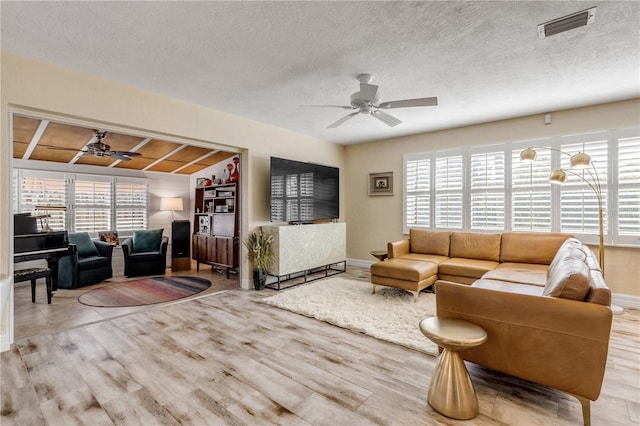 living room featuring ceiling fan, a healthy amount of sunlight, and a textured ceiling