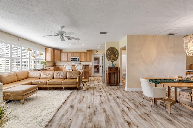 living room featuring light hardwood / wood-style flooring, a textured ceiling, and ceiling fan