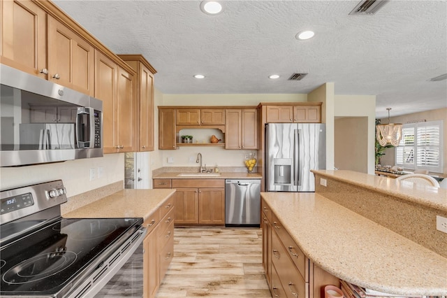 kitchen with appliances with stainless steel finishes, light hardwood / wood-style flooring, a textured ceiling, and sink