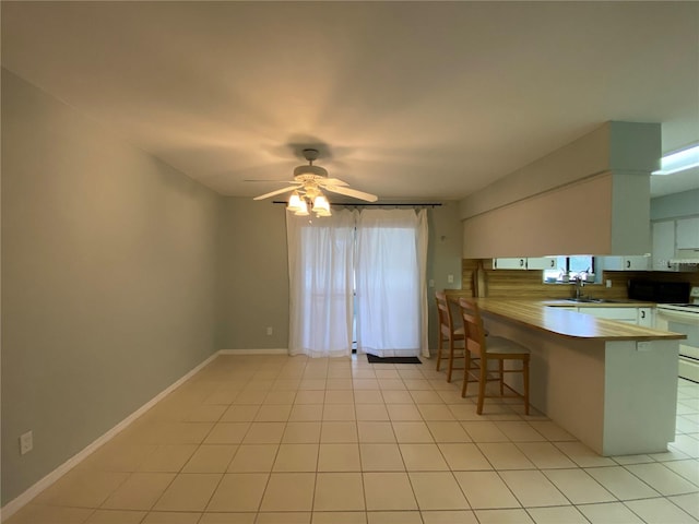 kitchen with a kitchen breakfast bar, white cabinets, decorative backsplash, kitchen peninsula, and white range oven