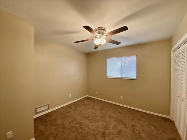 unfurnished bedroom with ceiling fan, a closet, and dark carpet