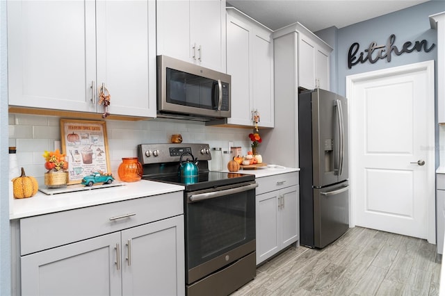 kitchen featuring light hardwood / wood-style floors, appliances with stainless steel finishes, backsplash, and white cabinets