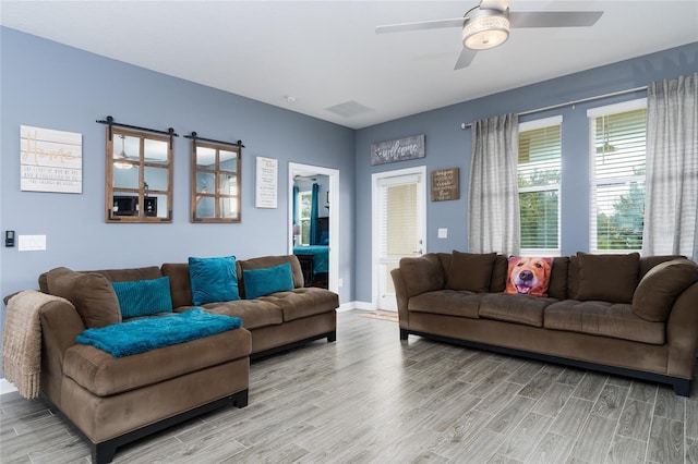 living room featuring light hardwood / wood-style floors, a barn door, and ceiling fan