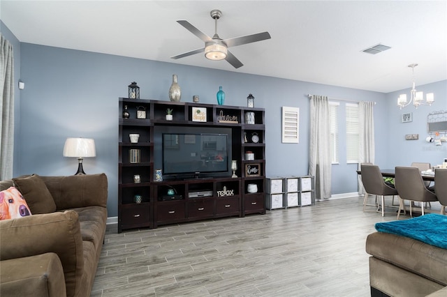 living room featuring ceiling fan with notable chandelier and light wood-type flooring