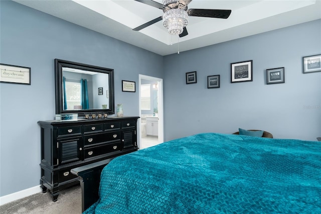 bedroom with ensuite bathroom, light colored carpet, and ceiling fan