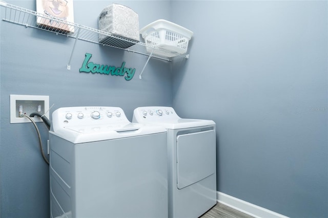 clothes washing area featuring washing machine and dryer and wood-type flooring