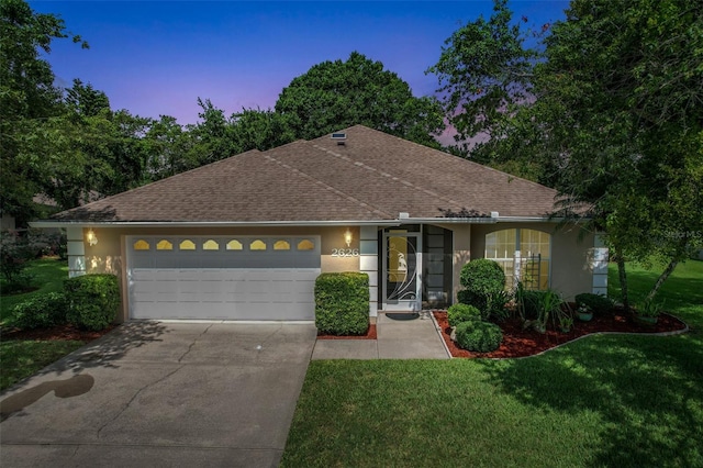 view of front of home with a garage and a lawn