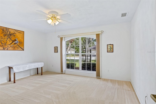 empty room featuring ceiling fan and light colored carpet