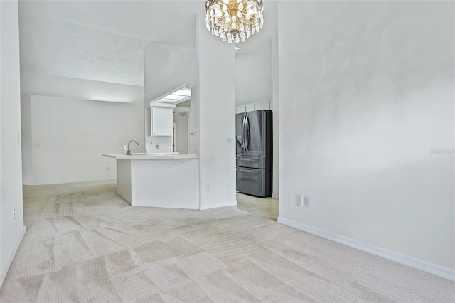 unfurnished living room with sink, a chandelier, and light colored carpet