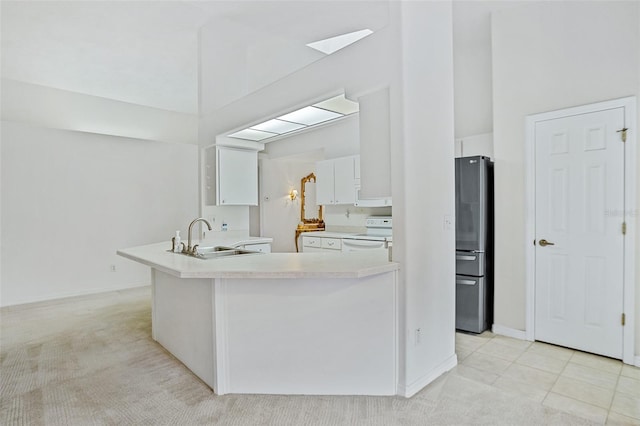 kitchen with stainless steel fridge, sink, white cabinets, and light colored carpet