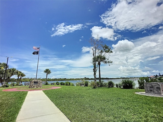 view of property's community with a water view and a lawn