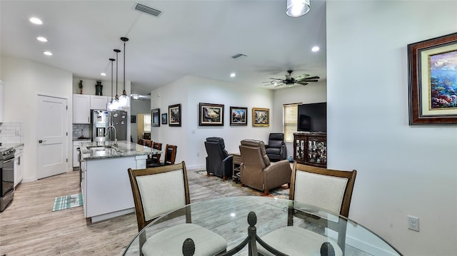 dining space with light hardwood / wood-style flooring, sink, and ceiling fan