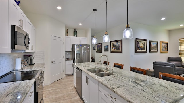 kitchen with light stone countertops, appliances with stainless steel finishes, sink, white cabinetry, and decorative backsplash