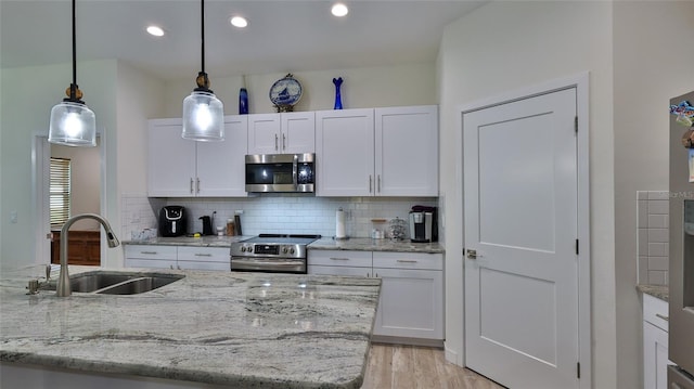 kitchen featuring appliances with stainless steel finishes, sink, pendant lighting, and white cabinets