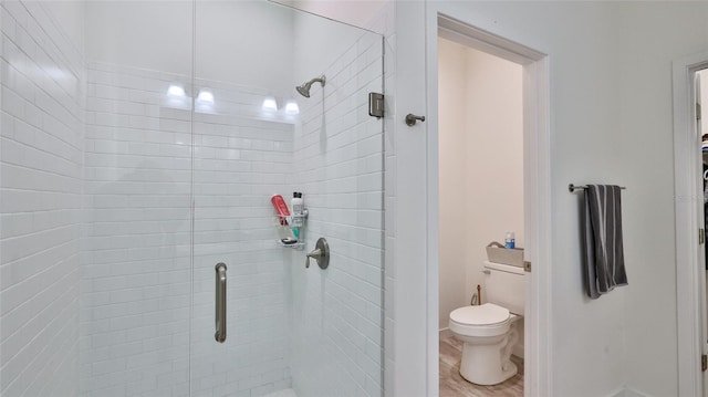 bathroom with toilet, wood-type flooring, and a shower with door