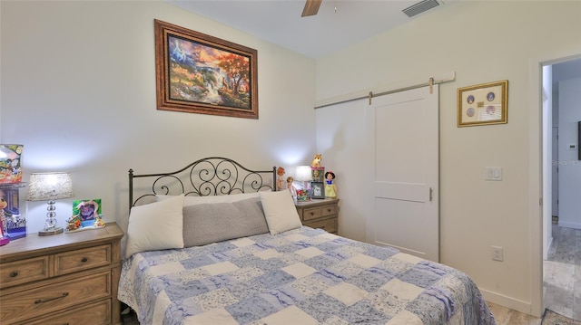 bedroom with a barn door and ceiling fan