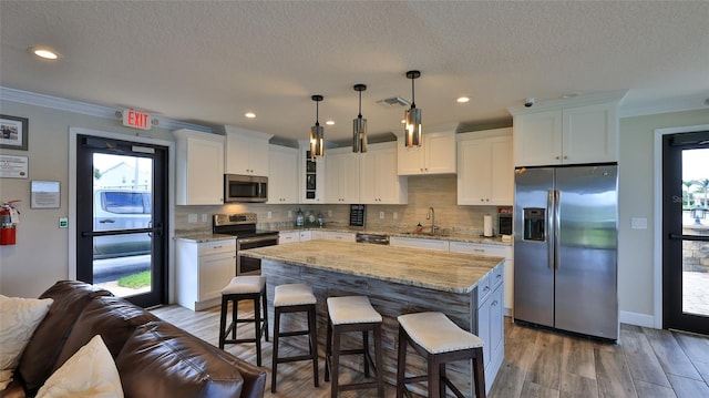 501 N Causeway Unit 2050, New Smyrna Beach, FL 32169 - kitchen featuring appliances with stainless steel finishes, white cabinets, a breakfast bar, backsplash, and ornamental molding