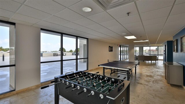 game room with expansive windows, a drop ceiling, baseboards, and a healthy amount of sunlight