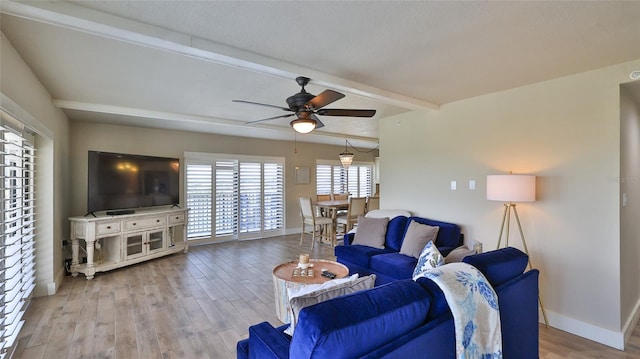 living area featuring beamed ceiling, wood finished floors, a ceiling fan, and baseboards