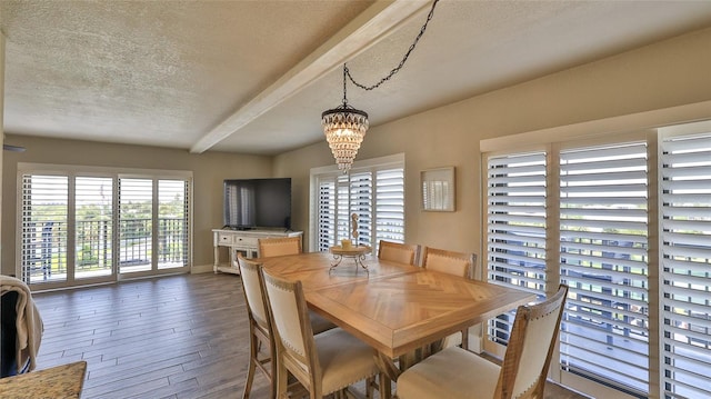 dining area featuring a notable chandelier, dark wood finished floors, a textured ceiling, beamed ceiling, and baseboards