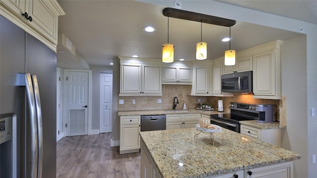 kitchen with appliances with stainless steel finishes, backsplash, a sink, and wood finished floors