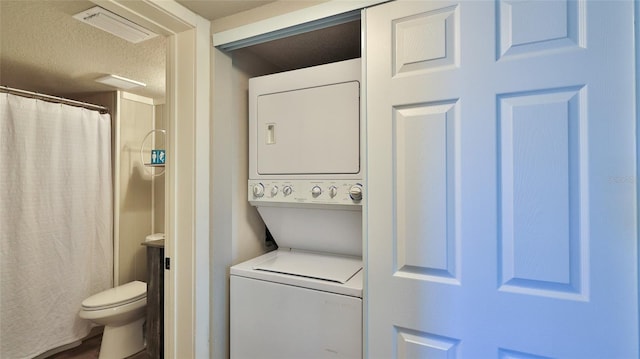 interior space with a textured ceiling, toilet, a shower with shower curtain, visible vents, and stacked washer and clothes dryer