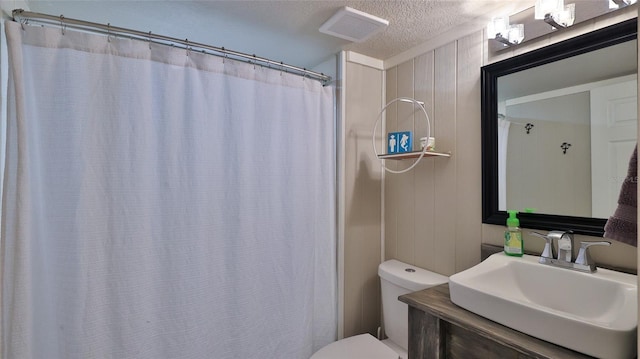 bathroom with a textured ceiling, toilet, vanity, visible vents, and a shower with curtain