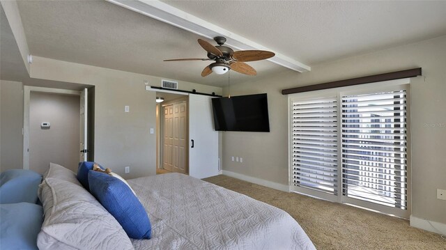 carpeted bedroom featuring a barn door, visible vents, a ceiling fan, a textured ceiling, and beam ceiling