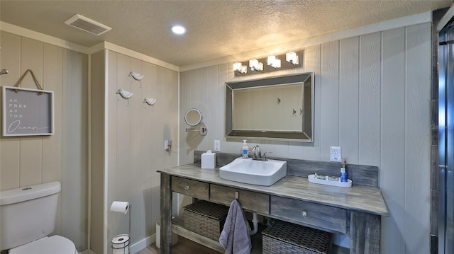 bathroom with toilet, visible vents, a textured ceiling, and vanity