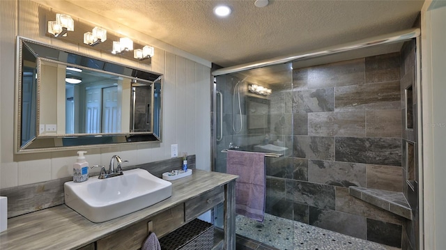 bathroom featuring a shower stall, a textured ceiling, and vanity