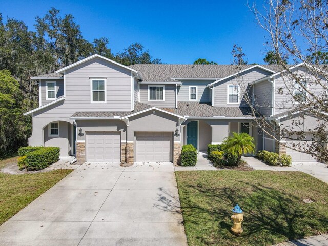679 Mount Olympus Blvd, New Smyrna Beach, FL 32168 - view of front of property featuring driveway, a front lawn, stone siding, an attached garage, and stucco siding