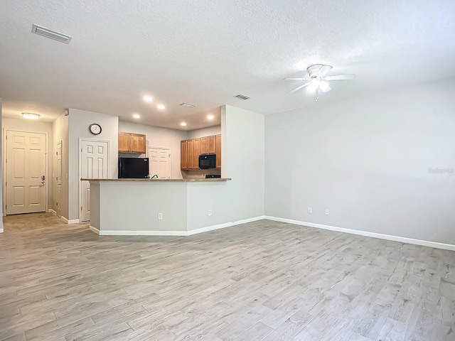 unfurnished living room featuring ceiling fan, a textured ceiling, and light wood-type flooring