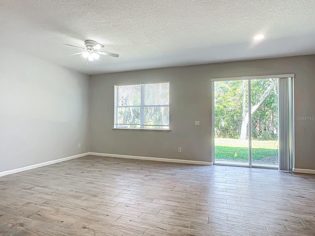 empty room featuring ceiling fan, a textured ceiling, and light hardwood / wood-style flooring