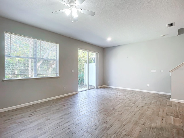 empty room with ceiling fan, a textured ceiling, and light wood-type flooring