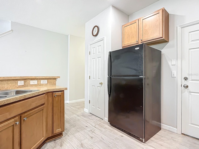 679 Mount Olympus Blvd, New Smyrna Beach, FL 32168 - kitchen featuring freestanding refrigerator, light wood-style floors, baseboards, and brown cabinets