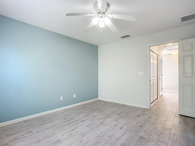 679 Mount Olympus Blvd, New Smyrna Beach, FL 32168 - spare room with light wood-type flooring, ceiling fan, a textured ceiling, baseboards, and attic access