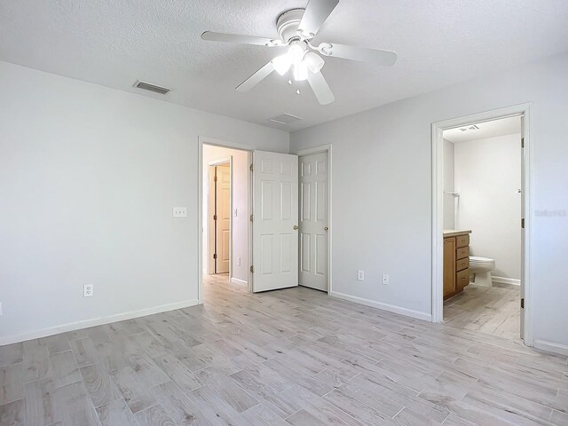 679 Mount Olympus Blvd, New Smyrna Beach, FL 32168 - unfurnished bedroom with light wood finished floors, baseboards, a textured ceiling, ensuite bath, and ceiling fan