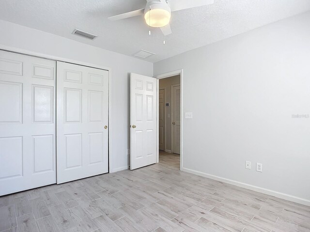 679 Mount Olympus Blvd, New Smyrna Beach, FL 32168 - unfurnished bedroom with light wood-style floors, a closet, baseboards, a ceiling fan, and a textured ceiling