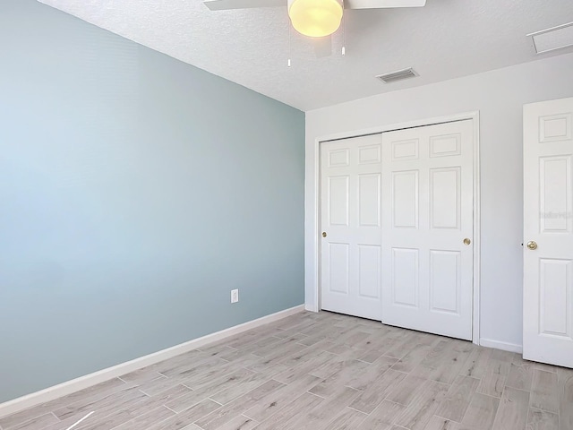 679 Mount Olympus Blvd, New Smyrna Beach, FL 32168 - unfurnished bedroom featuring light wood finished floors, a closet, baseboards, a textured ceiling, and a ceiling fan