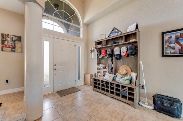 mudroom featuring a towering ceiling and tile patterned flooring