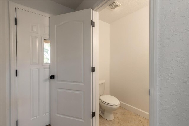 2266 Hawks Cove Cir, New Smyrna Beach, FL 32168 - bathroom with tile patterned floors, a textured wall, toilet, and baseboards