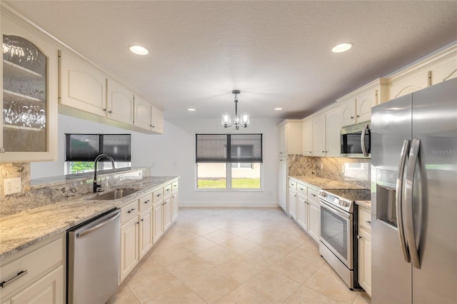 kitchen featuring sink, light stone countertops, a notable chandelier, decorative light fixtures, and appliances with stainless steel finishes