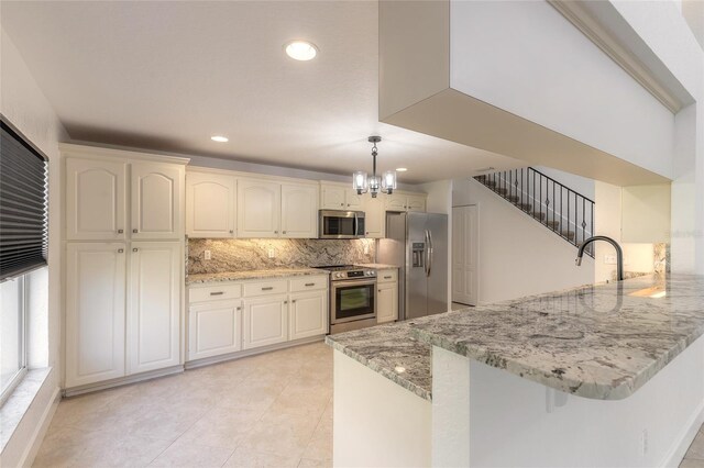 2266 Hawks Cove Cir, New Smyrna Beach, FL 32168 - kitchen featuring appliances with stainless steel finishes, a peninsula, a chandelier, tasteful backsplash, and light stone countertops
