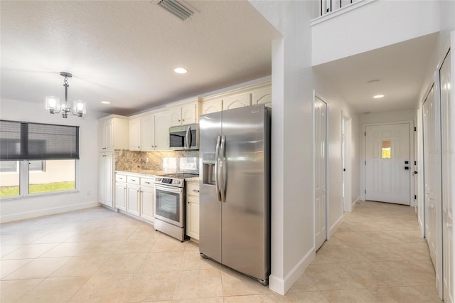 kitchen featuring appliances with stainless steel finishes, decorative light fixtures, decorative backsplash, light tile patterned floors, and a chandelier