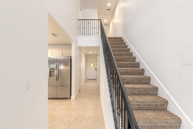 2266 Hawks Cove Cir, New Smyrna Beach, FL 32168 - stairs featuring tile patterned floors, a towering ceiling, and a textured wall