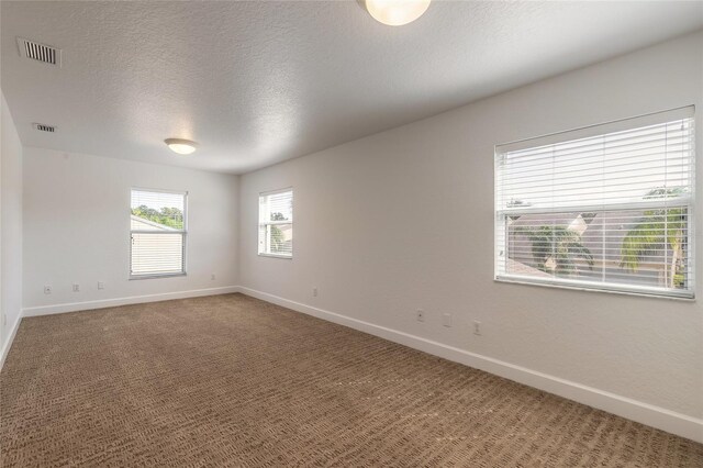 unfurnished room with a textured ceiling and carpet floors