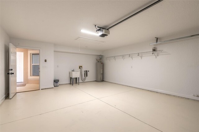 2266 Hawks Cove Cir, New Smyrna Beach, FL 32168 - garage featuring a garage door opener, water heater, a sink, and baseboards