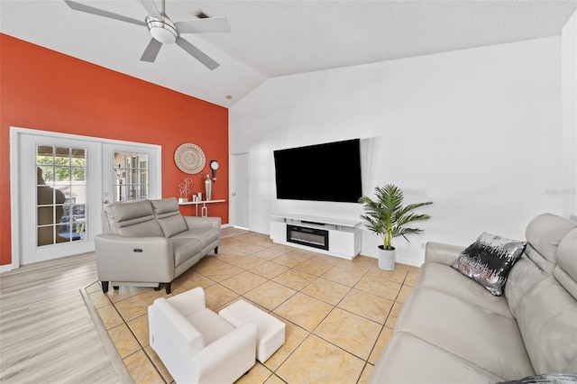 living room with french doors, vaulted ceiling, light wood-type flooring, a textured ceiling, and ceiling fan